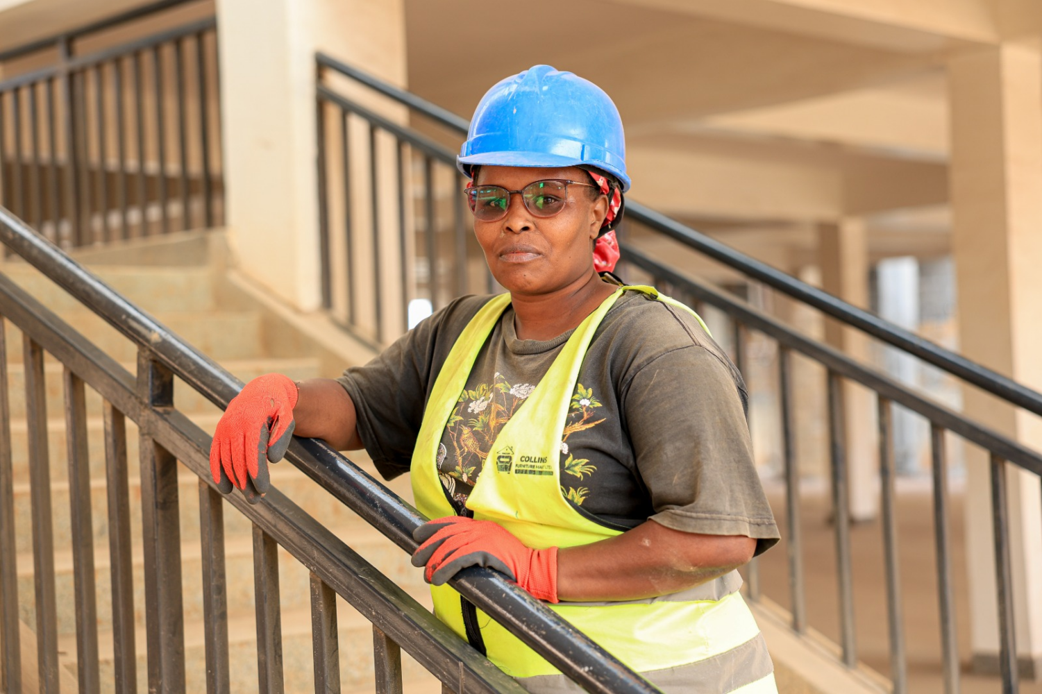 Lillian Wairimu stands on a staircase at the Field Marshal Muthoni Economic Stimulus Programme (ESP) Market in Nyeri, where she has gained practical construction skills and earned an income that has strengthened her financial independence.